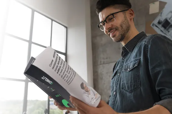 Homme consultant une brochure Comelit dans un intérieur lumineux.